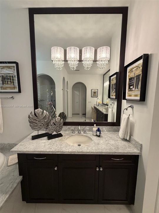 SMALLER OF TWO SEPARATE VANITIES WITH DESIGNER CRYSTAL LIGHTS AND MARBLE COUNTER TOP.