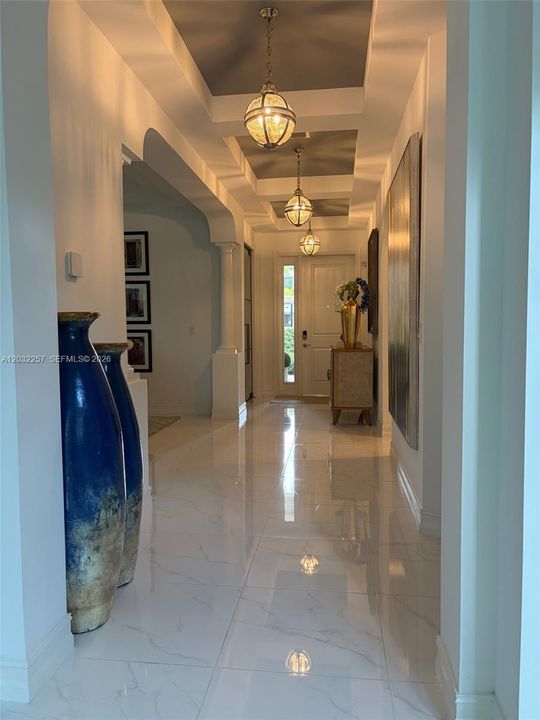 ENTRY HALLWAY, DECORATED BEAUTIFULLY WITH THREE TRAY CEILINGS, EACH DISPLAYING A GLASS GLOBE PENDANT.