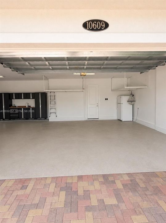 GARAGE DOUBLE DOOR SIDE. CUSTOM CABINET WALL AND DOUBLE CEILING RACKS.  ALSO A REFRIGERATOR WITH FREEZER.