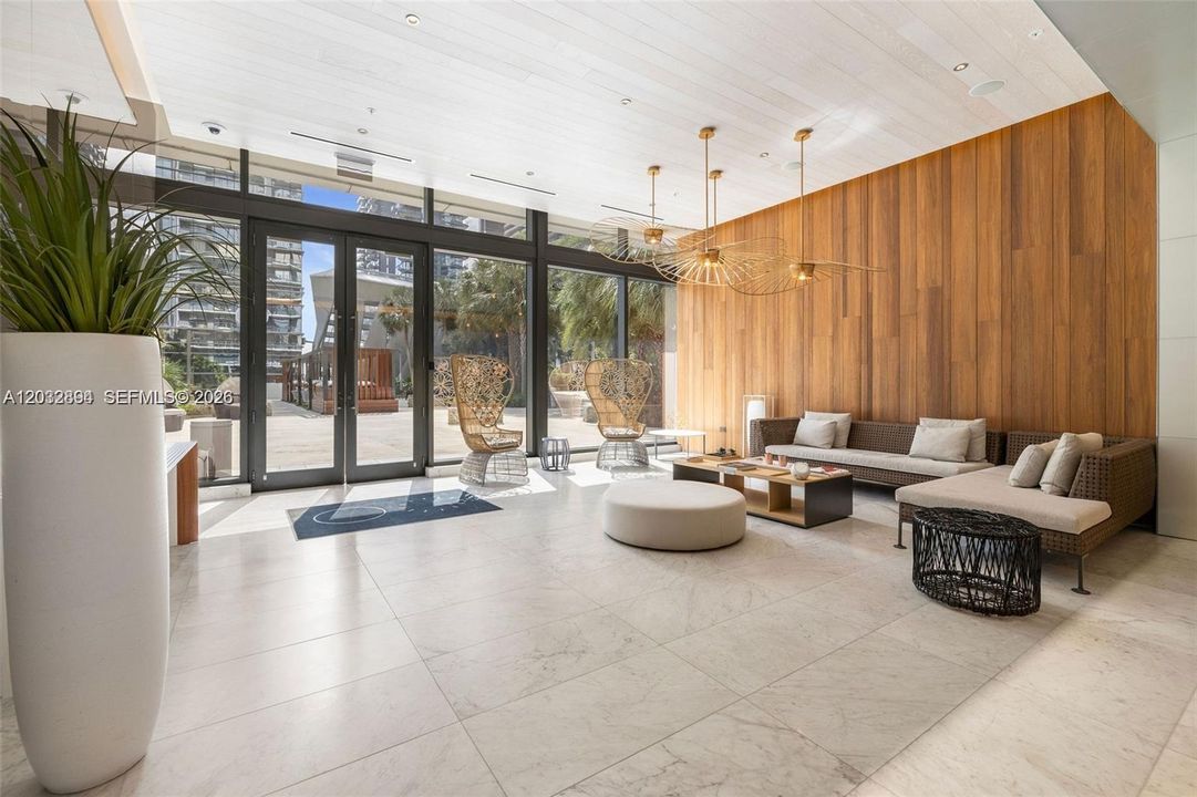 Elegant Rise lobby with floor-to-ceiling glass, warm wood accents and lounge seating.