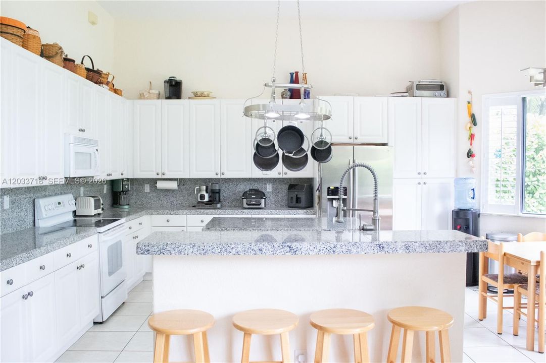 Huge kitchen with high ceilings, center island, snack counter and breakfast table.