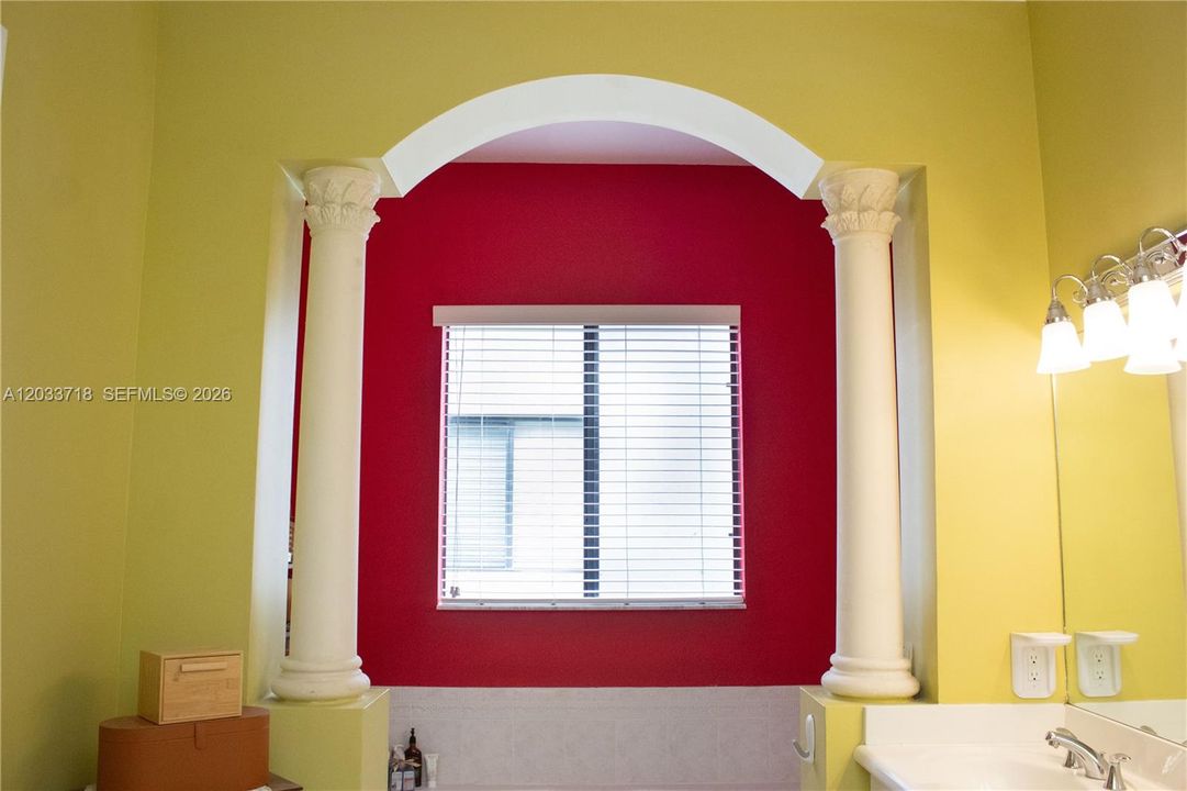A huge bathtub and a window along with high ceilings provide a relaxing luxurious feel in the Primary Bath