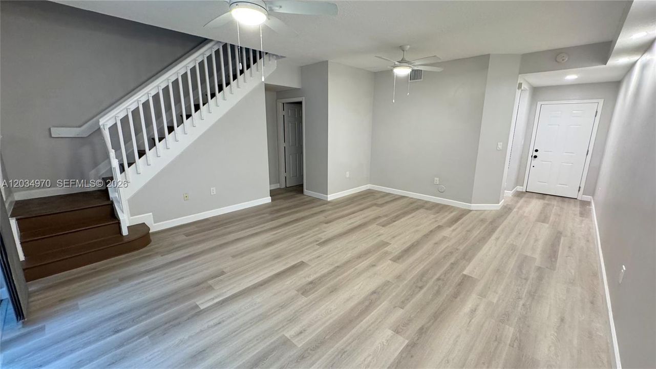 Open living and dining area featuring a guest bathroom to the left and convenient storage space tucked beneath the staircase.