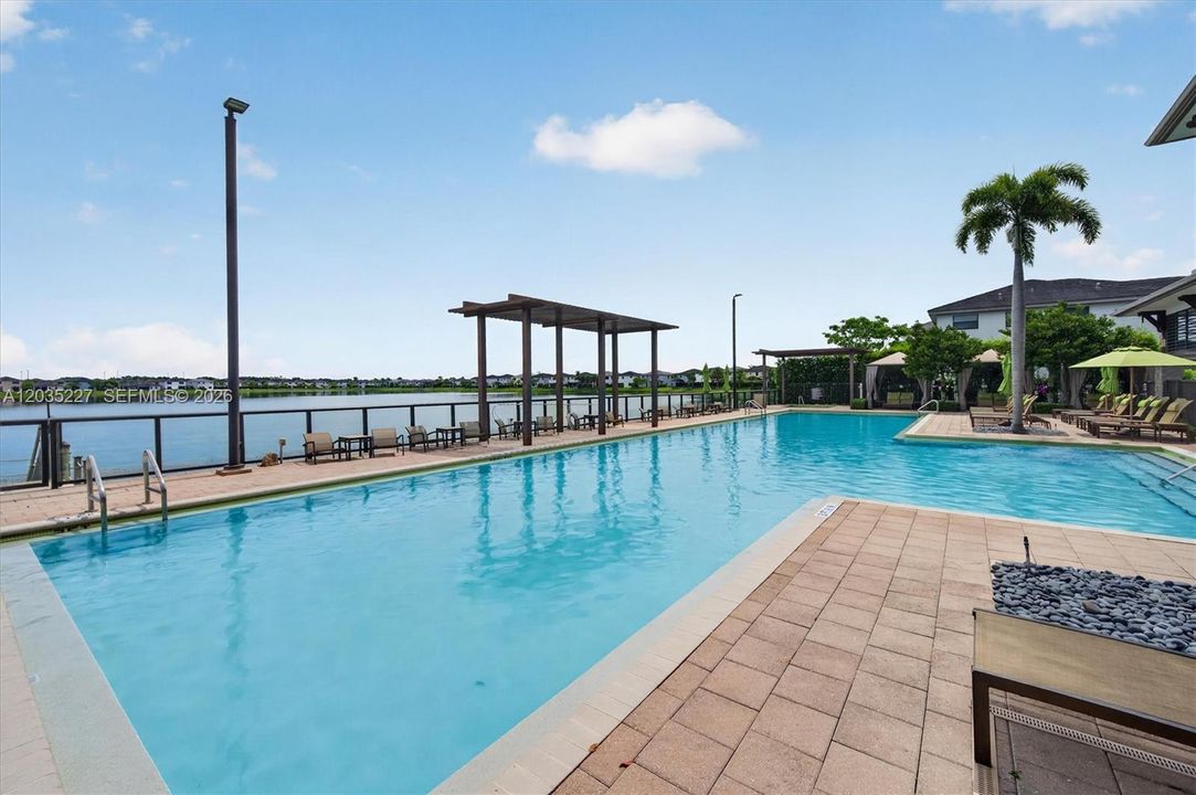 Expansive covered terrace with poolside views, offering both dining and lounge seating for residents to enjoy. A striking sphere chandelier and stacked-stone columns add architectural flair to this resort-style outdoor space.