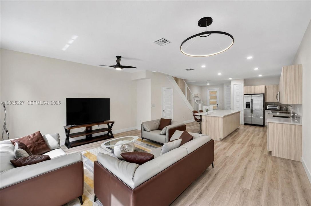 Open-concept living space seamlessly flowing into the gourmet kitchen, perfect for entertaining. Designer lighting and wide-plank flooring tie the modern aesthetic together throughout the spacious and sleek downstairs.
