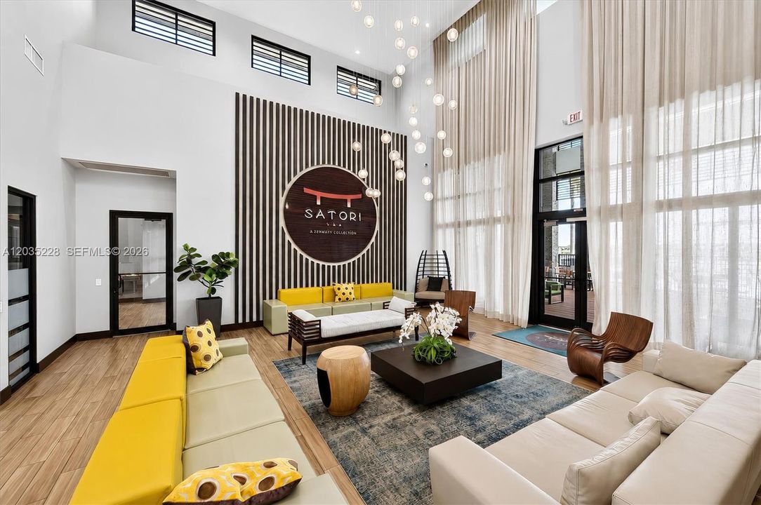 Striking double-height lobby with a dramatic bubble chandelier and bold designer furnishings in citrus tones. A statement signature wall and curated mix of textures create an upscale, hotel-inspired first impression.