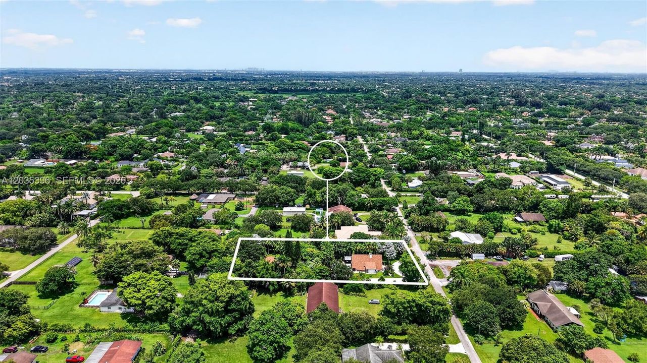 Large property with gorgeous grounds and mature trees, view of guest house on left and main house on right, separated by fence