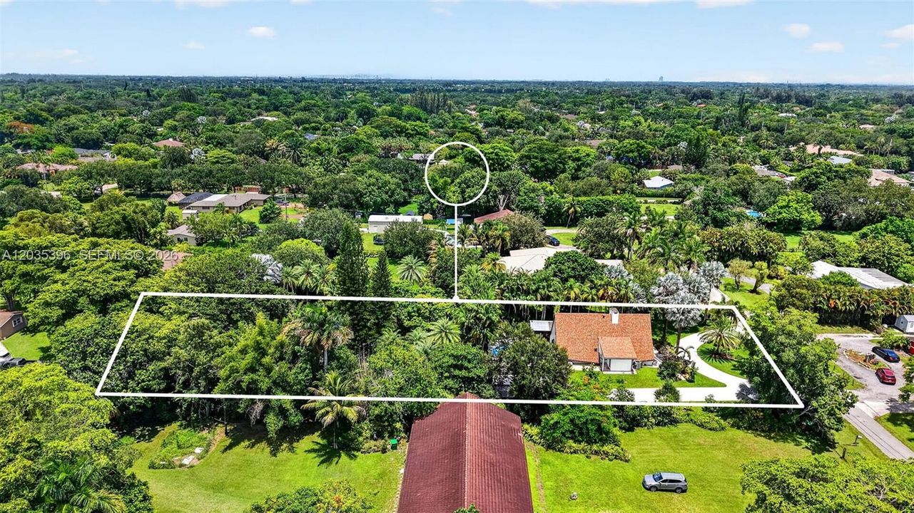 Large property with gorgeous grounds and mature trees, view of guest house on left and main house on right, separated by fence