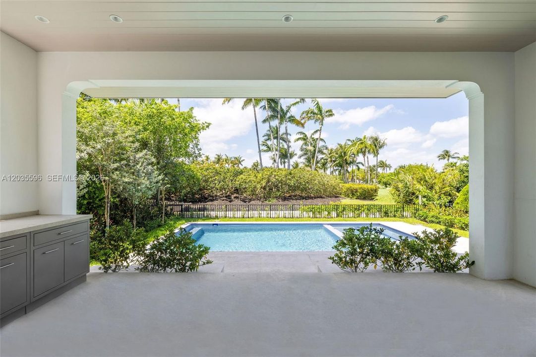Outside living room with full kitchen overlooks pool
