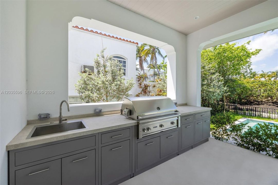 Outside living room with kitchen overlooks pool