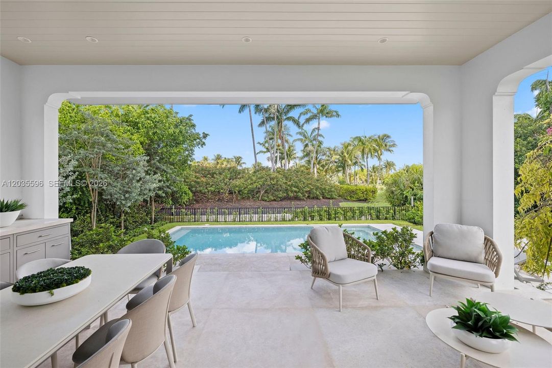 Outside living room with kitchen overlooks pool
