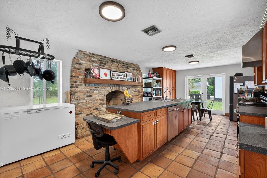 Large kitchen in with stone fireplace in single-family home