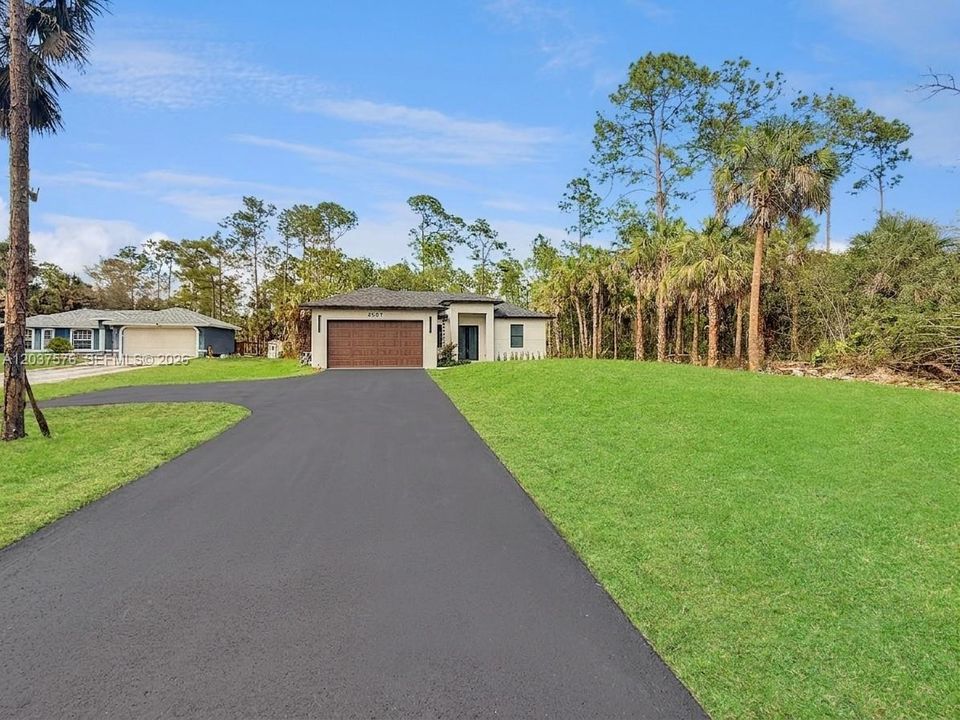 Contemporary single-story residence featuring a smooth stucco exterior, a dark shingle roof, and an attached two-car garage.