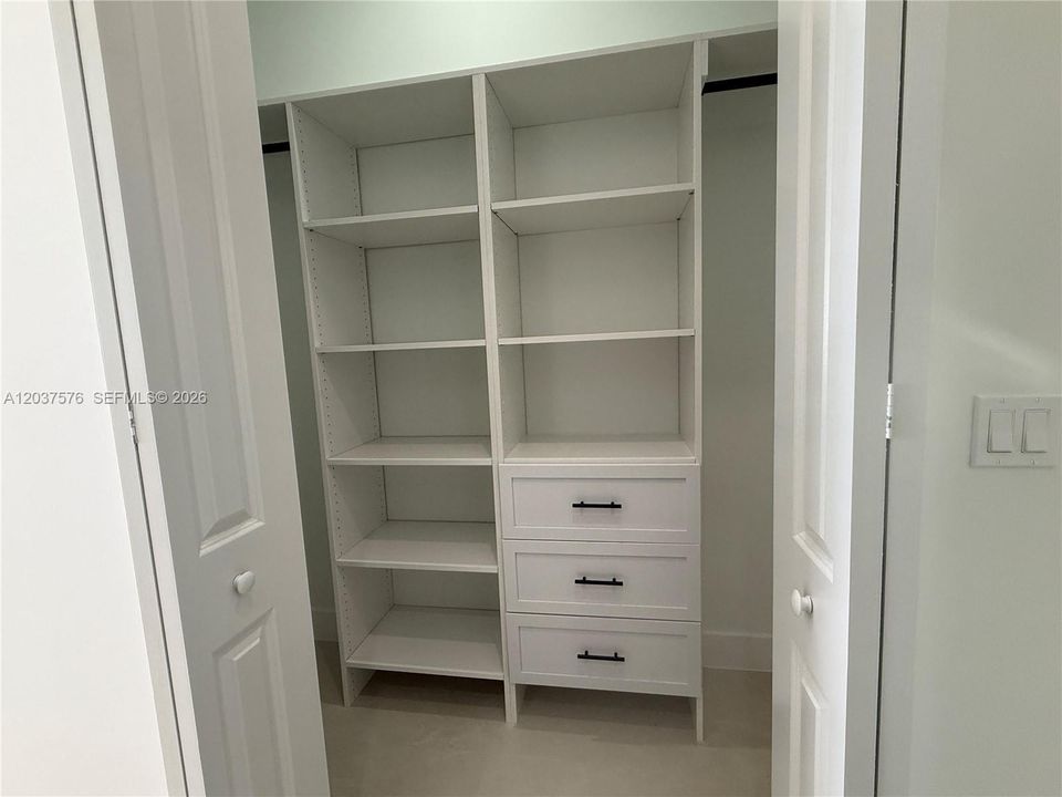 Custom closet system with white shelving, integrated drawers, and matte black hardware