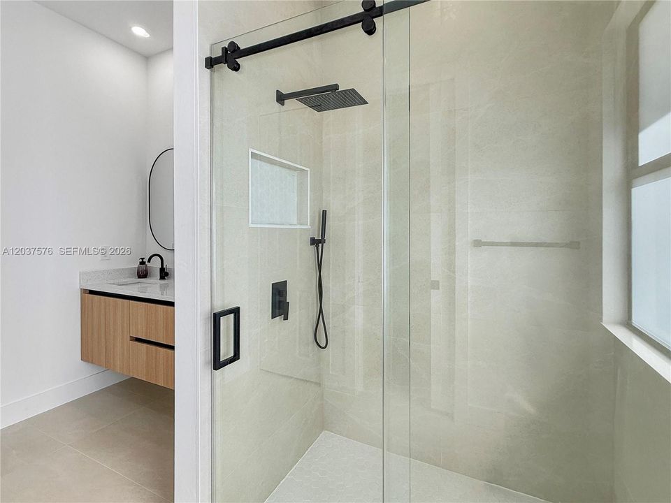 Contemporary shower enclosure with clear glass paneling and a matte black barn-style hardware system