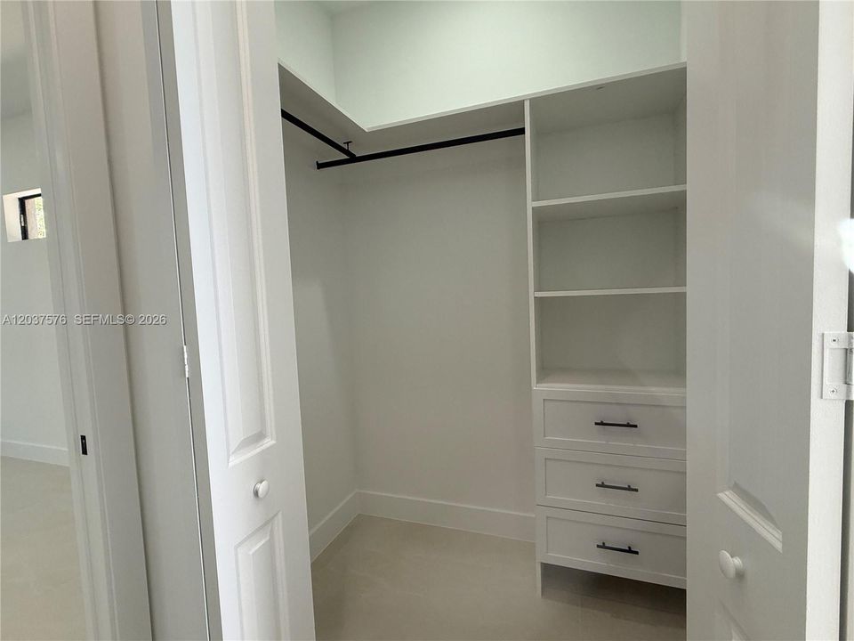 Custom closet system with white shelving, integrated drawers, and matte black hardware