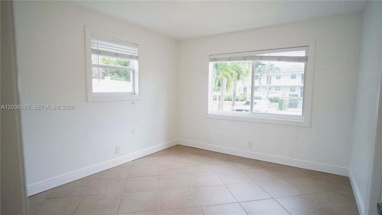 Neutral-toned ceramic tile flooring, clean white wall finishes, and dual windows with horizontal blinds