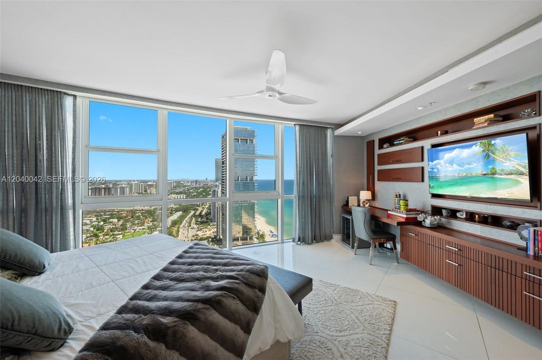Luxurious primary bedroom with sweeping ocean and city views.