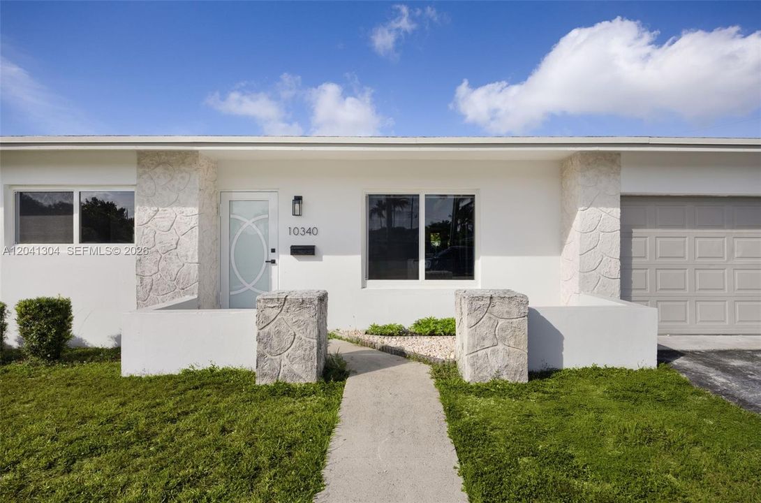 Front Entry – Inviting covered entrance featuring decorative stone accents and a modern frosted-glass front door. Thoughtfully designed details create a polished arrival experience.