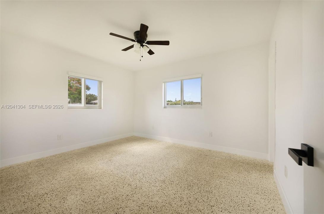 Primary Bedroom – Spacious primary bedroom enhanced by multiple windows and a ceiling fan for year-round comfort. The airy design creates a relaxing retreat.