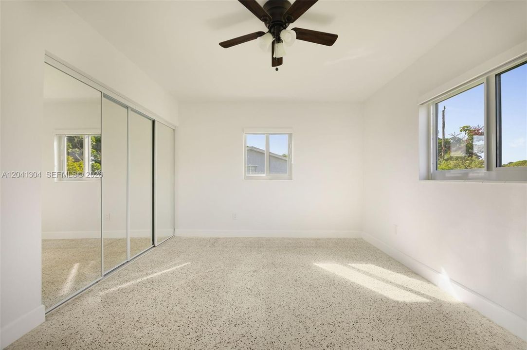 Primary Bedroom – Generously sized primary suite featuring mirrored closet doors that help maximize light and visual space. A bright, inviting setting with ample storage.