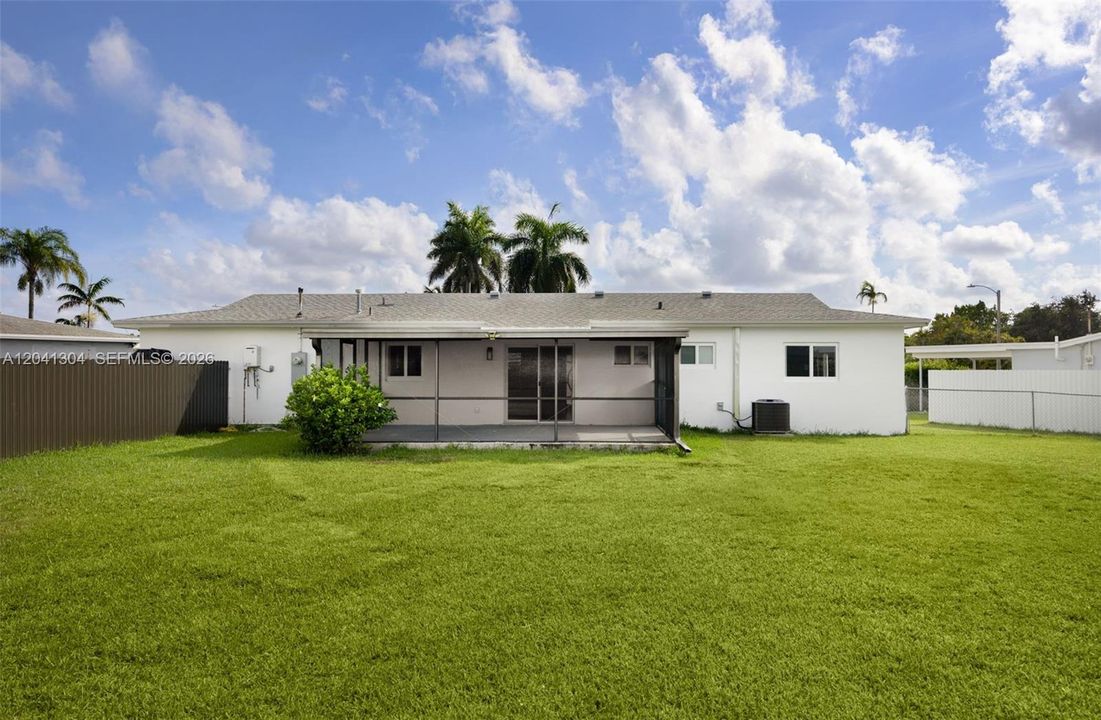 Backyard & Rear Exterior – Large fenced backyard with plenty of open green space for recreation, gardening, or outdoor gatherings. The screened patio extends the home's indoor-outdoor living appeal.