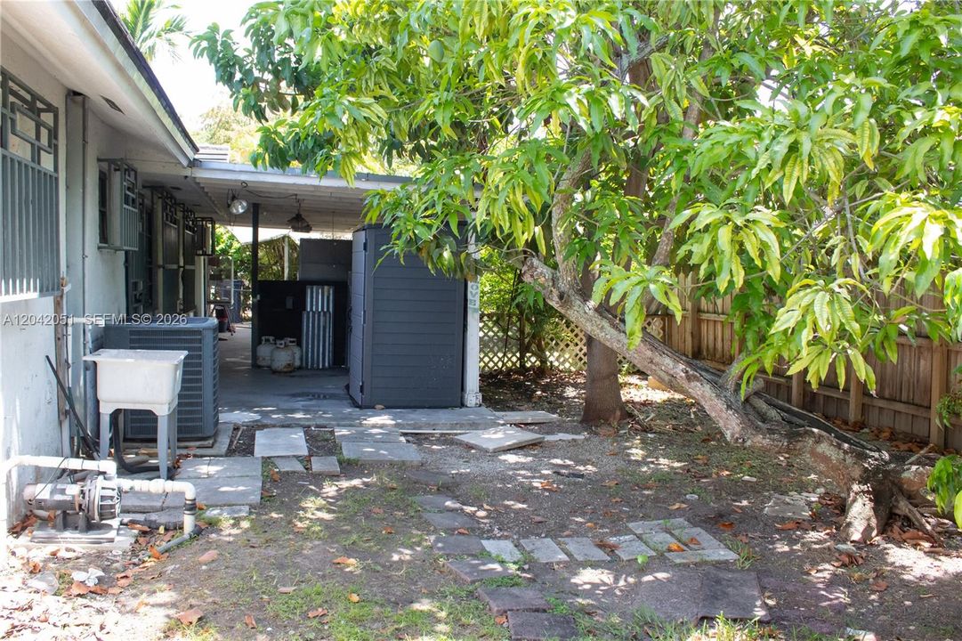 The yard is spacious but it currently has a patio with a roof and trees and a storage shed.