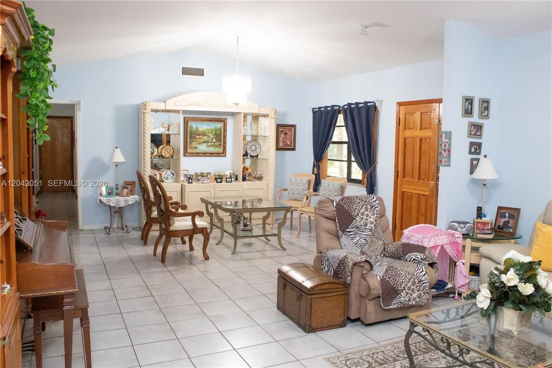 The main entrance is on the right, thru the wood double doors. There are vaulted ceilings and uniform tile throughout. The hallway seen on the left, leads to the 4 bedrooms as well as the hallway bath.