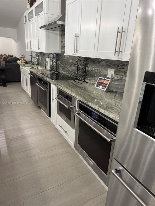 The kitchen's counter depth refrigerator, two ovens, microwave/oven, dishwasher, ceramic stove top, hood, and Kohler farm sink. All appliances are top of the line, KitchenAid, appliances.