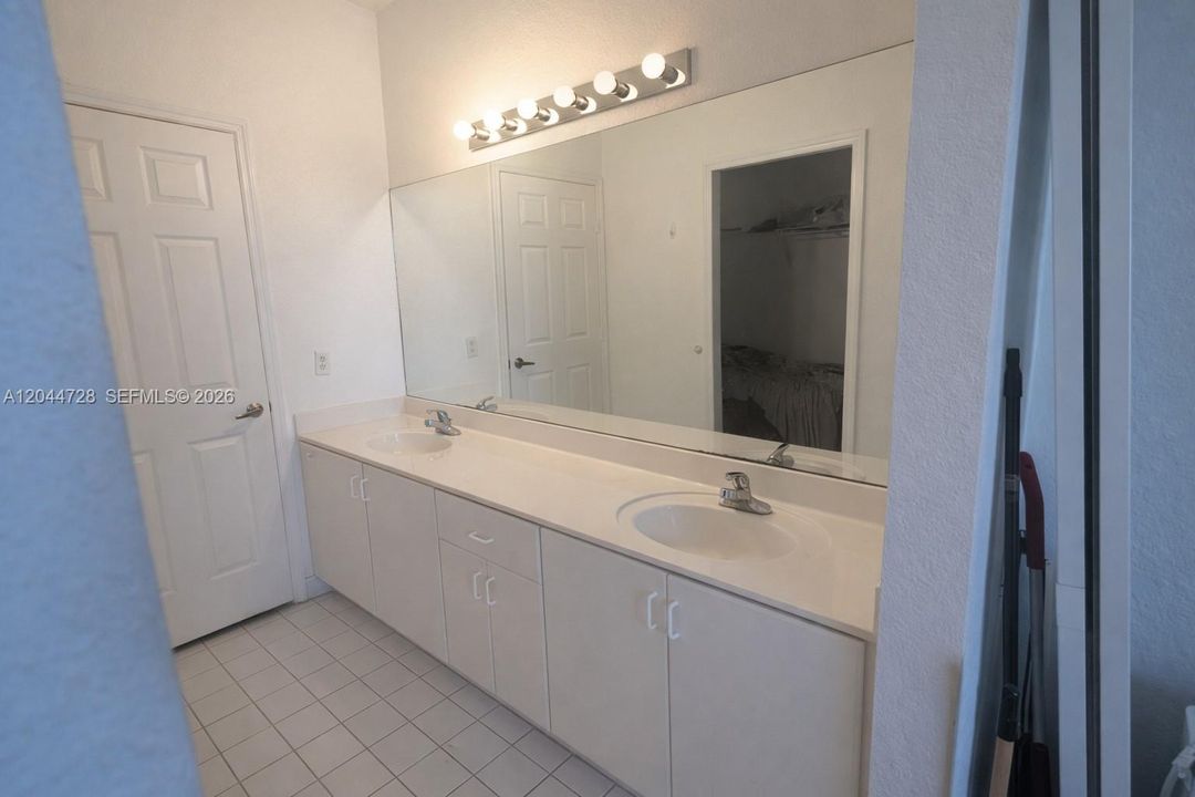 1st Master Bathroom with double-sink vanity, large mirror, and ample storage. Clean tile flooring and practical layout with great natural flow.