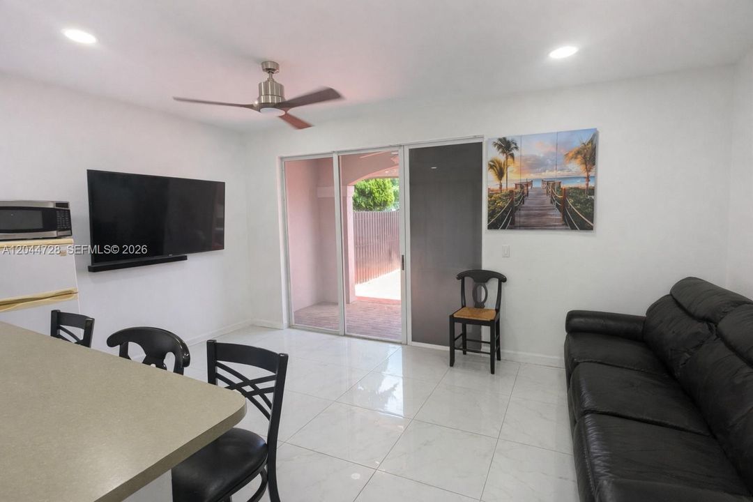 Bright living area with clean tile flooring, and large sliding doors that open to the patio. Functional layout with ceiling fan, and comfortable seating.