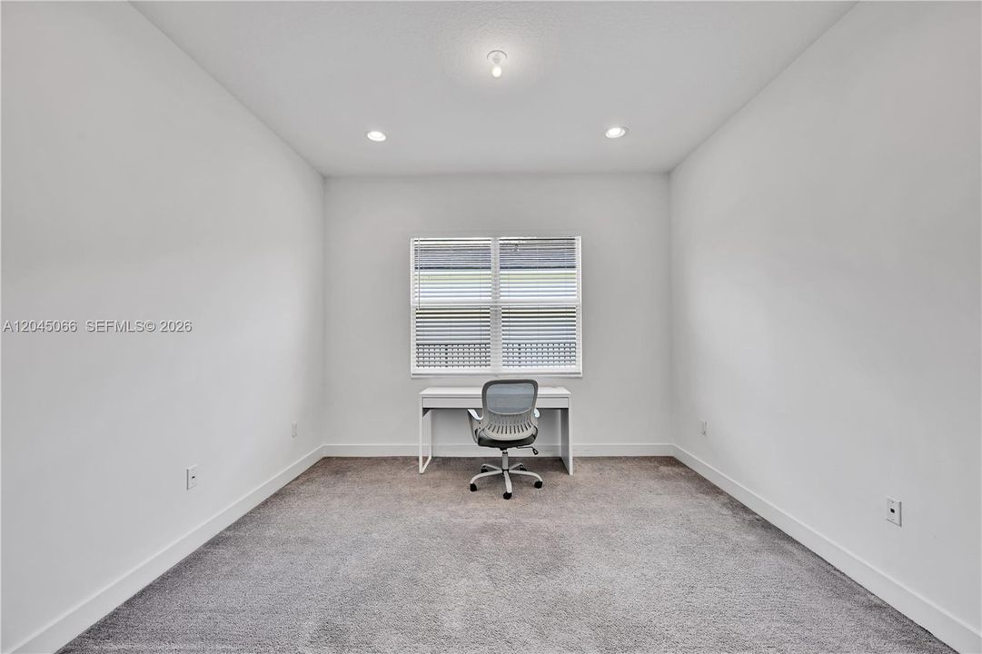 Neutral interior featuring wall-to-wall carpeting, recessed ceiling lighting, and a double-pane window with installed blinds