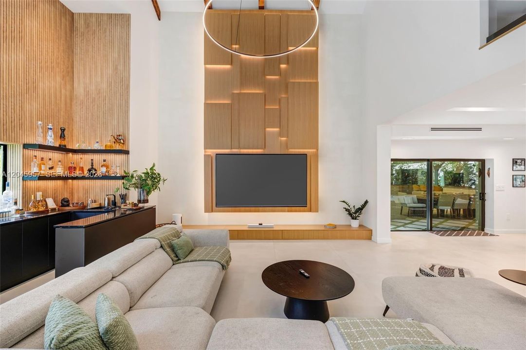 The heart of the home, with soaring two-story ceilings, dramatic architectural volume, and a custom feature wall creates an unforgettable first impression