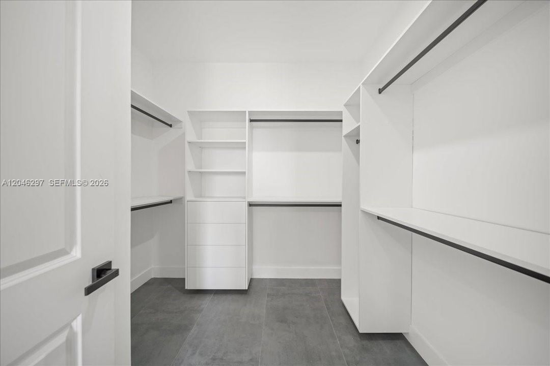 The expansive closet offers built-in shelving, drawer storage, and abundant hanging space, creating a clean and functional luxury wardrobe experience.