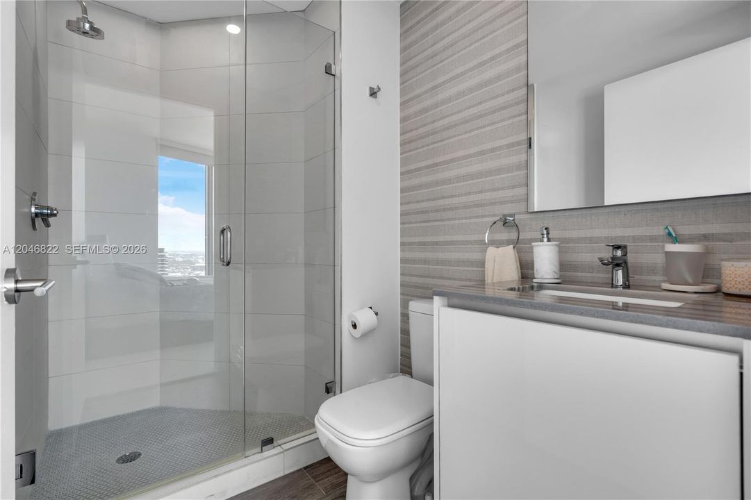 Full bath with glass-enclosed shower and spa-style tile
