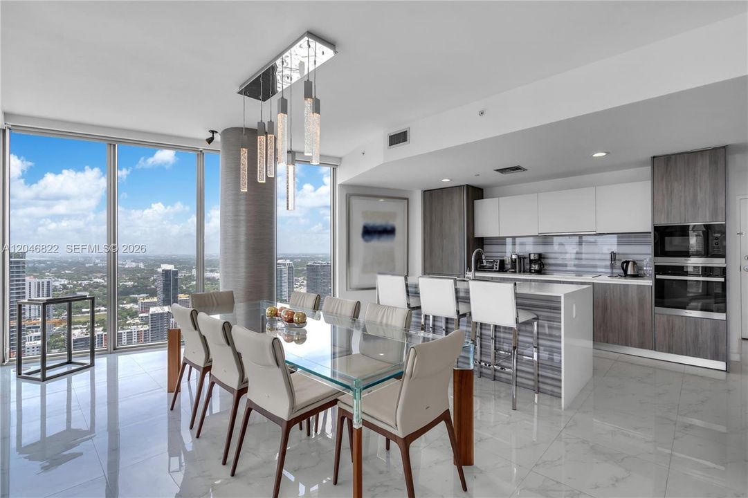Dining area beneath designer pendants with panoramic city views