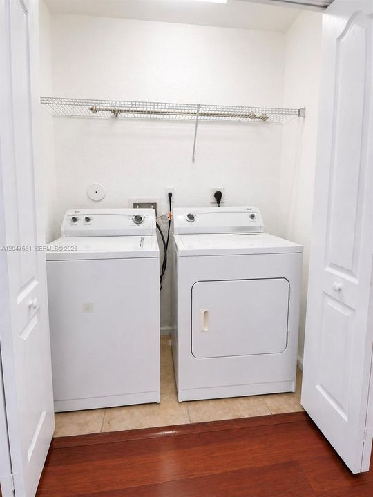 Convenient indoor laundry closet complete with a washer and dryer, plus an overhead storage shelf for added organization.