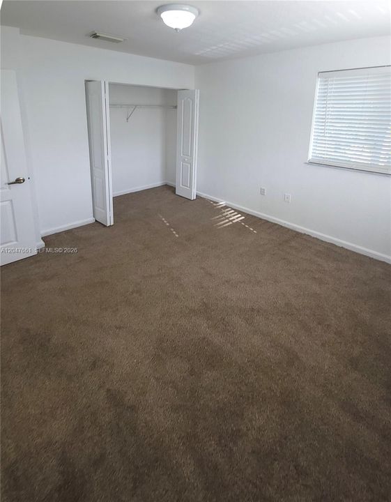 Spacious secondary bedroom featuring plush carpeting, abundant natural light, and a generous closet.