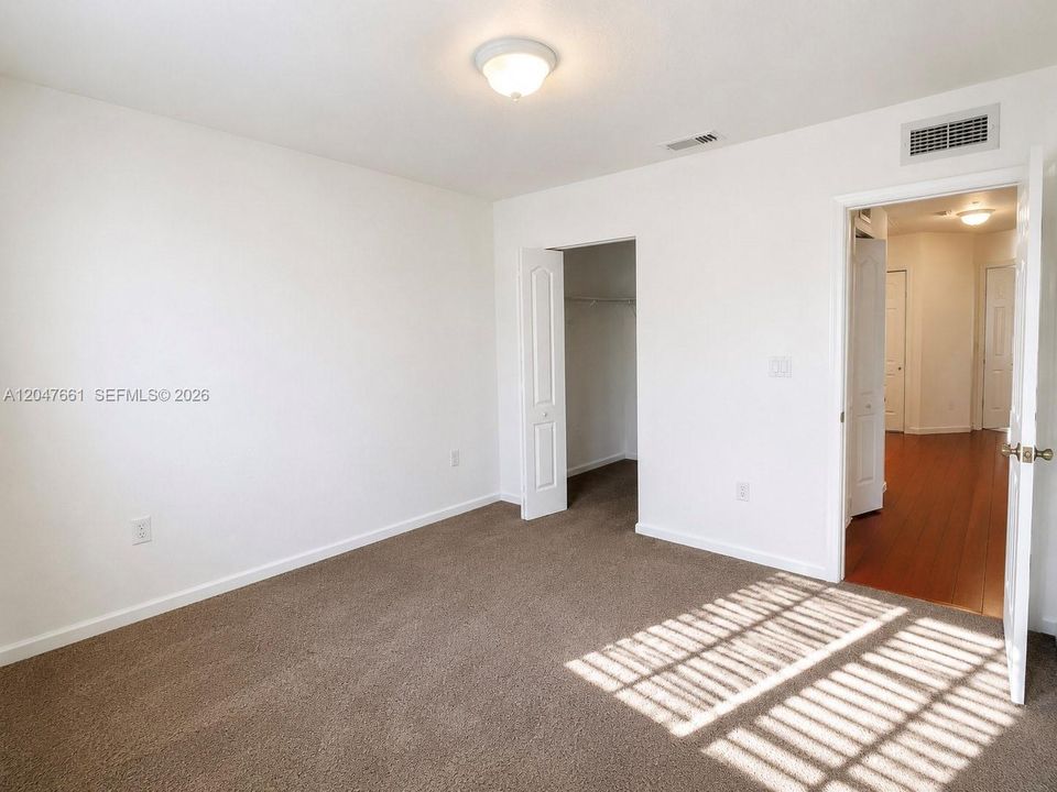 Spacious third bedroom on the second level featuring plush carpeting and a private walk-in closet.