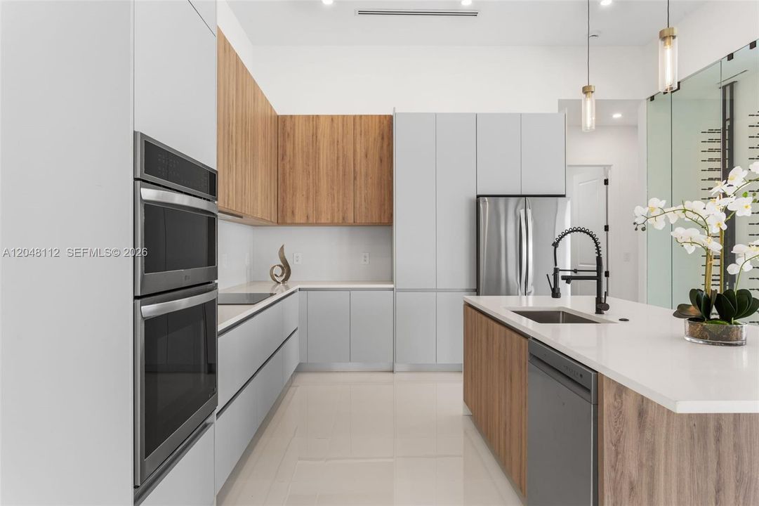 The EXPANSIVE ISLAND offers FLEXIBLE SEATING for CASUAL DINING or FORMAL GATHERINGS, and a FULL QUARTZ BACKSPLASH adds MODERN SOPHISTICATION