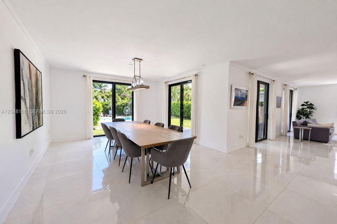 large, naturally-lit dining area with space for guests.  floor-to-ceiling doors lead to back yard terrace and pool.