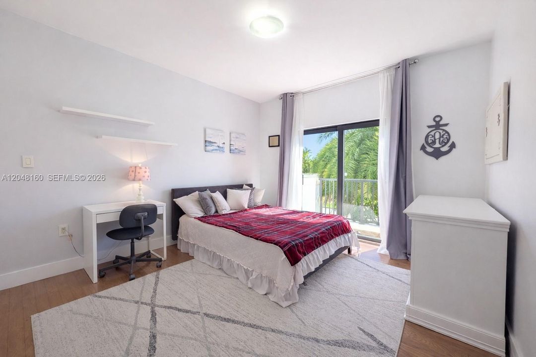 second floor bedroom with ensuite bathroom, large built-in closet and floor-to-ceiling glass door to a small terrace facing a mature palm tree and front yard.