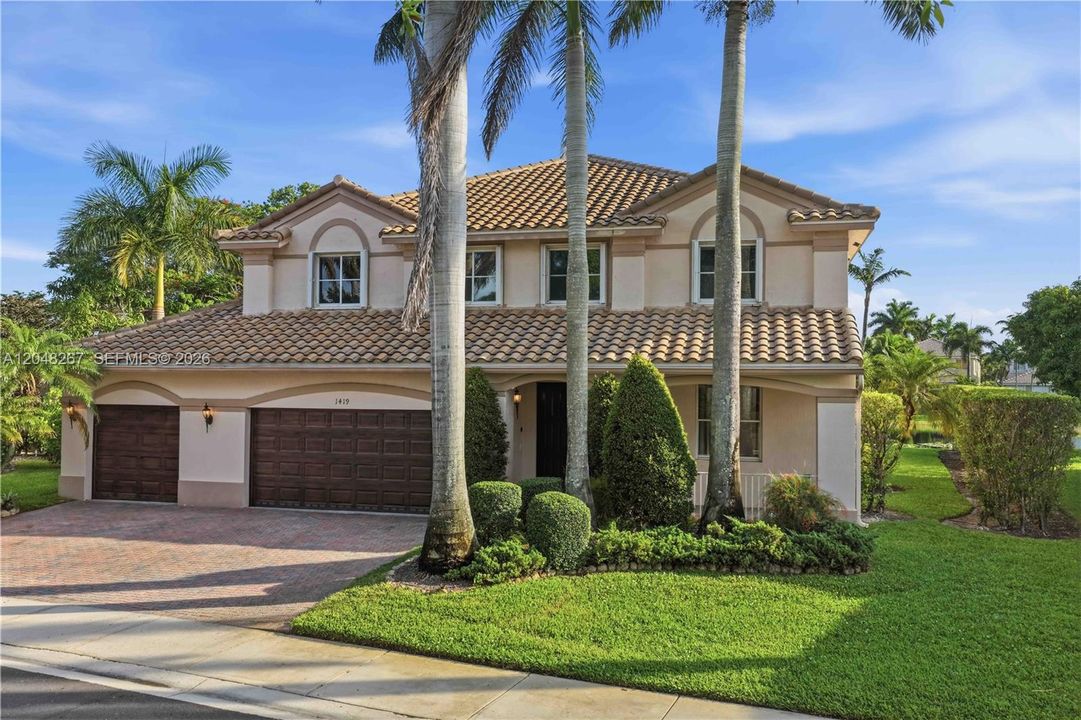 Three-car garage and lush greenery.