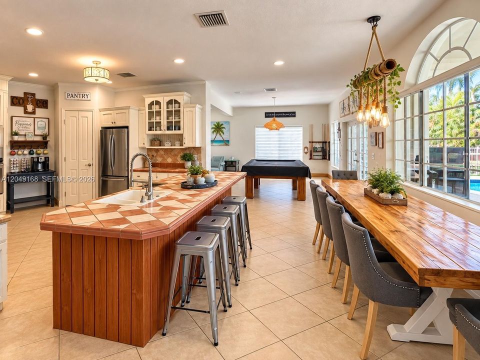 Kitchen featuring a center island with tile countertops, wood cabinetry, recessed lighting, and a multi-light chandelier