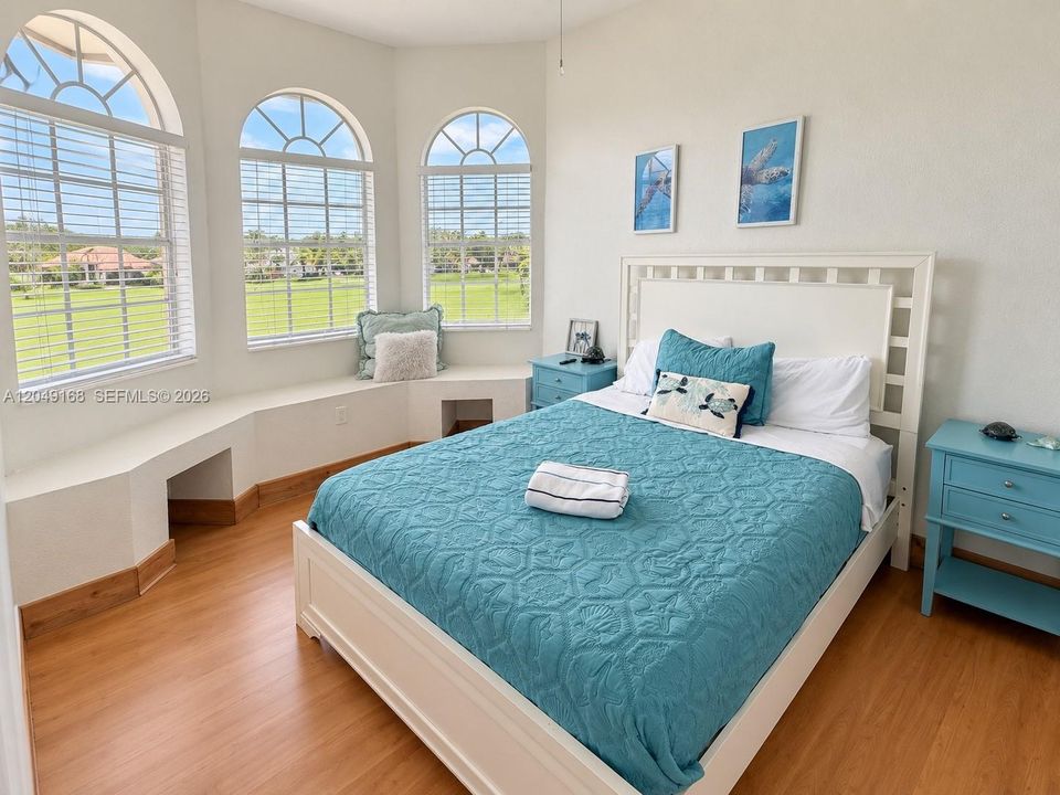 Bedroom featuring wood-finish flooring, three arched windows, and a built-in window bench