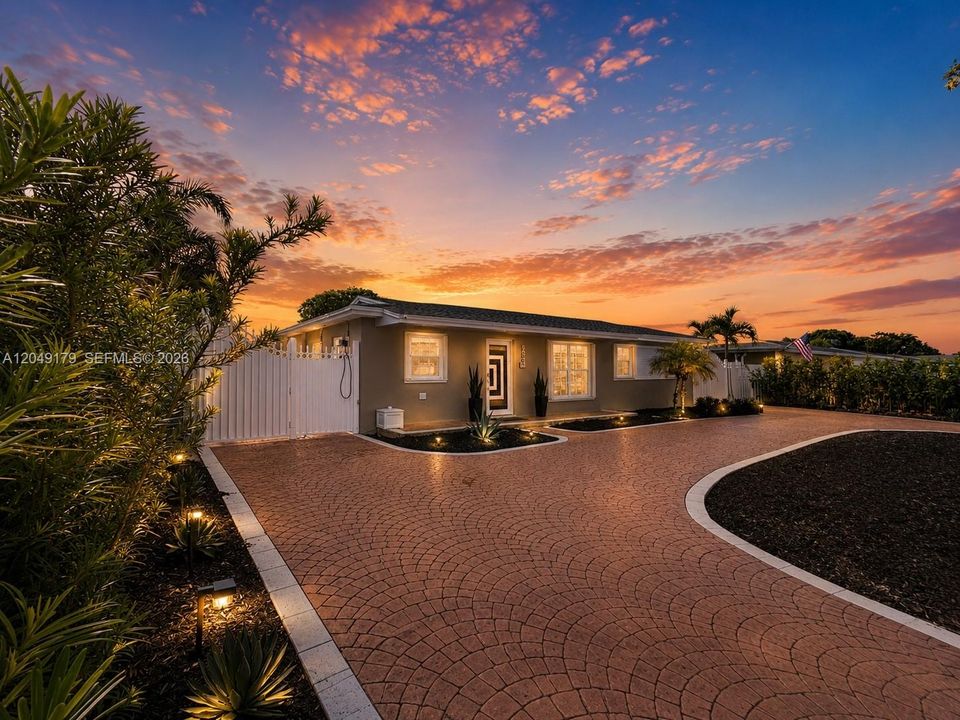 A must-see! Breathtaking twilight curb appeal welcomes you to this private 7,875 sq. ft. homesite featuring a grand motorized gated entrance, expansive stamped concrete circular driveway with additional parking, lush Podocarpus privacy landscaping, impact-rated front door, hurricane shutters, newer August 2023 roof, and beautifully illuminated grounds that create an unforgettable first impression.