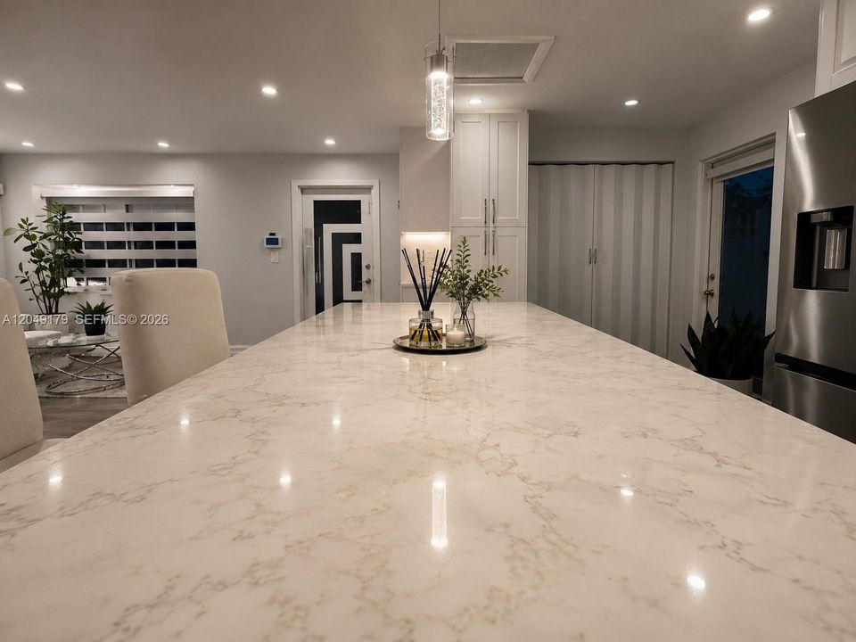 Beautifully renovated kitchen featuring white shaker cabinetry, quartz countertops, stainless steel appliances, a designer tile backsplash, and abundant storage.