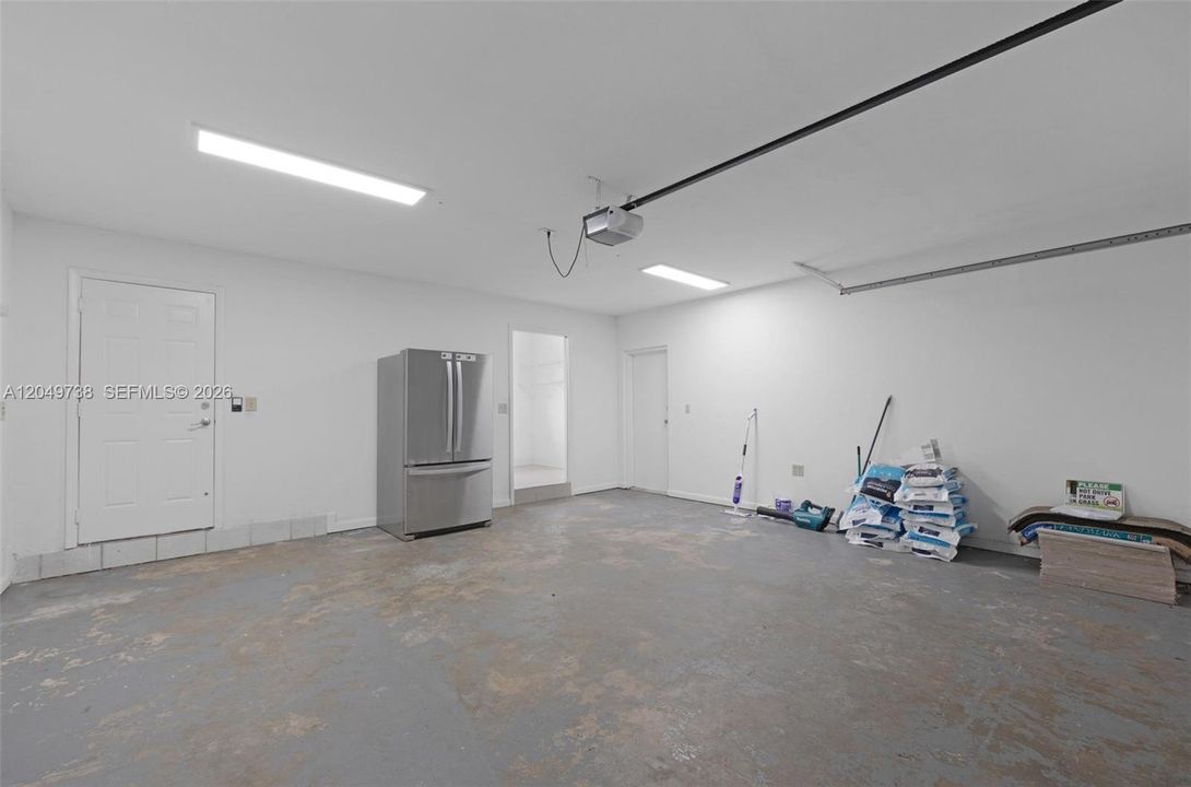 Spacious garage with automatic garage opener, side door to yard access and utility room