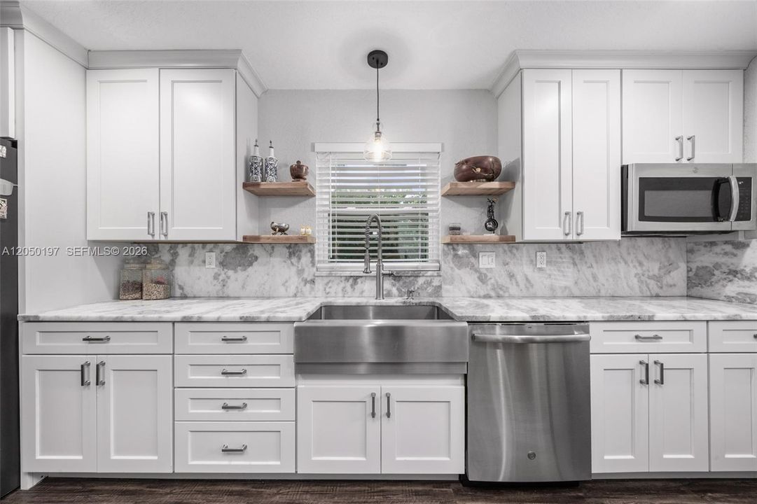Kitchen with stainless farmers sink, white cabinetry, granite & stainless appliances