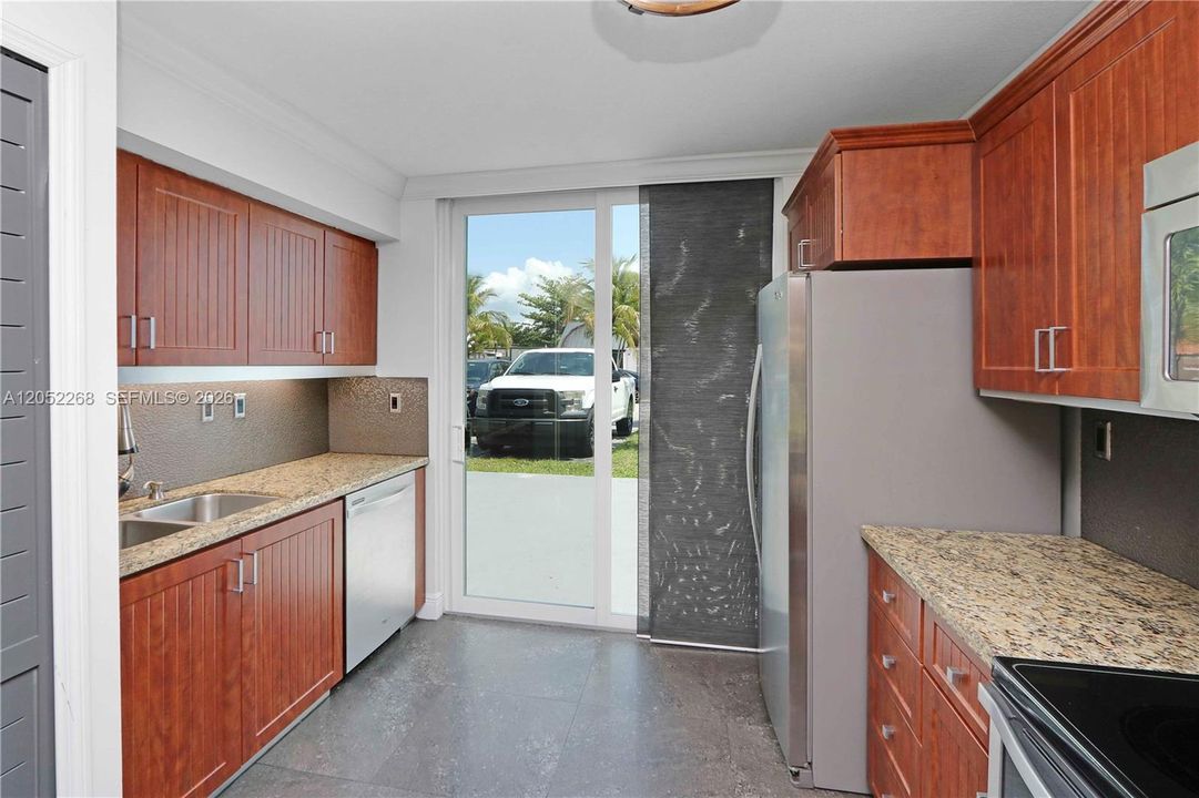 Cocina luminosa con salida directa al exterior mediante puerta corrediza, optimizando la ventilación y la iluminación natural en todo el espacio.